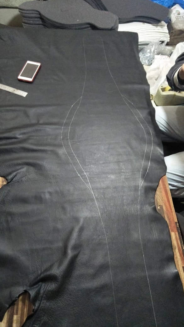 Detailed view of leather cutting process for handcrafted belt strap.