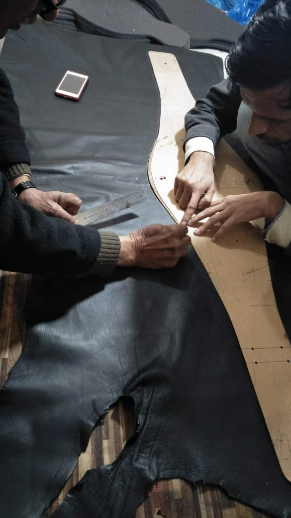 Cutting the leather strap by hand using pattern lines for a custom belt.