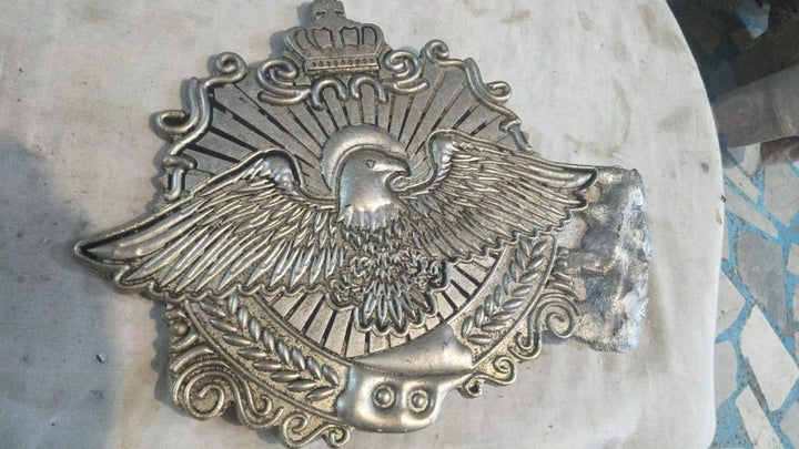 Raw metal eagle plate just released from the mold during custom belt production.